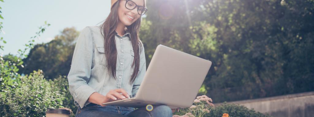 Woman sitting on ledge with laptop