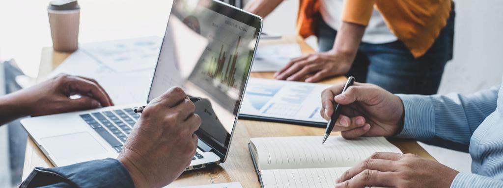 Group of three people at a desk working on a laptop