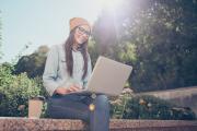 Woman sitting on ledge with laptop
