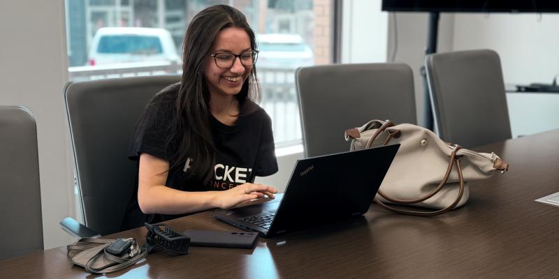 Rocket Concepts employee smiling while sitting at table with laptop